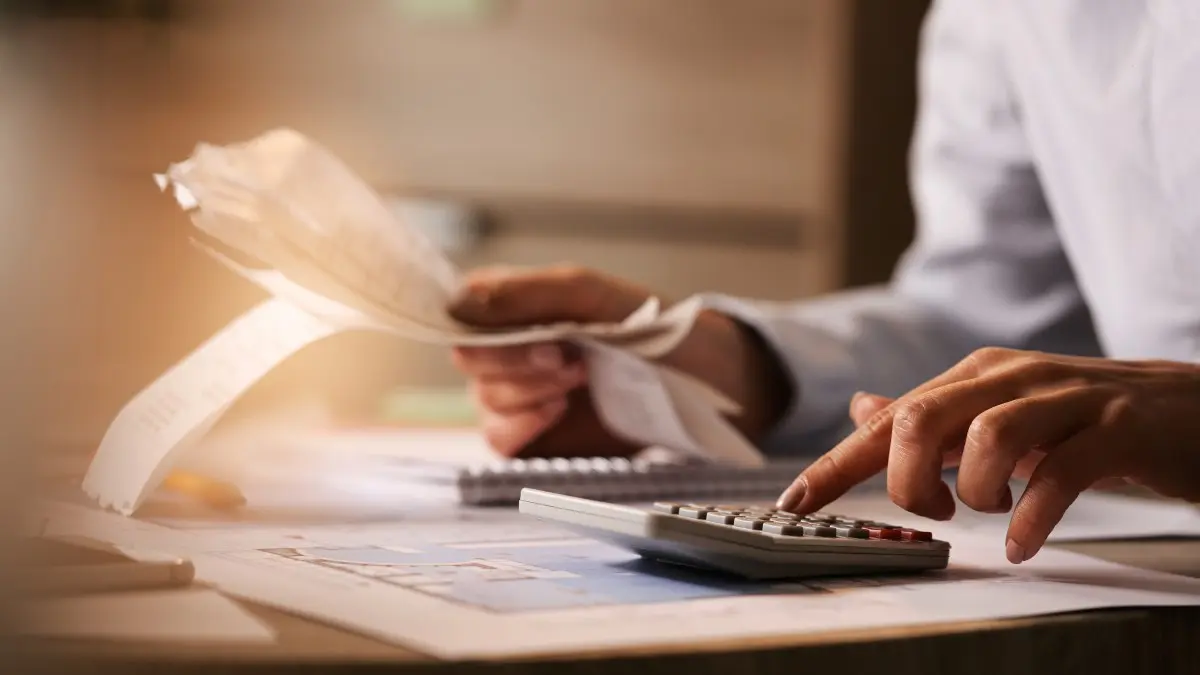 Close-up of economist using calculator while going through bills and taxes in the office.